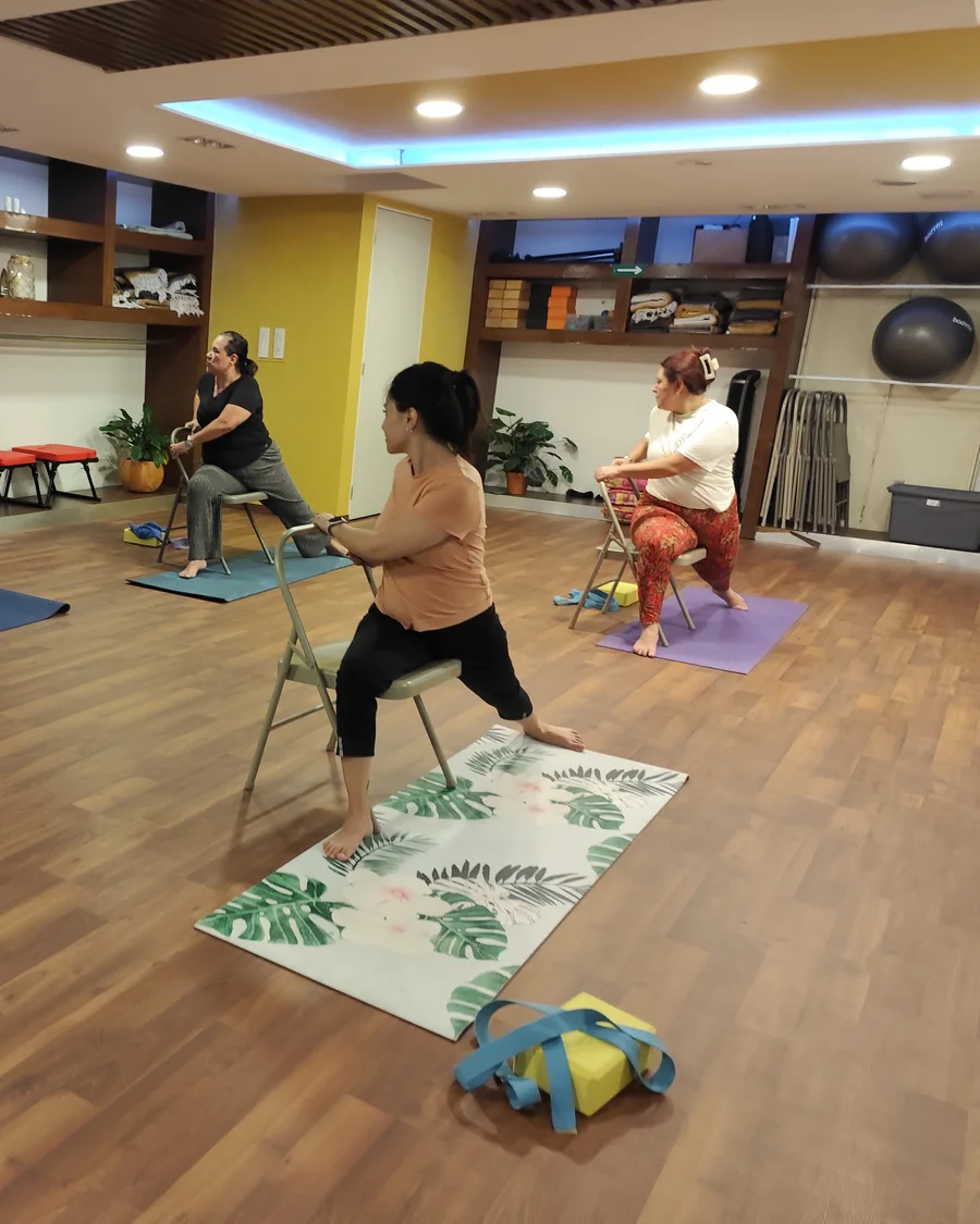Grupo practicando yoga en silla, distintas edades y cuerpos